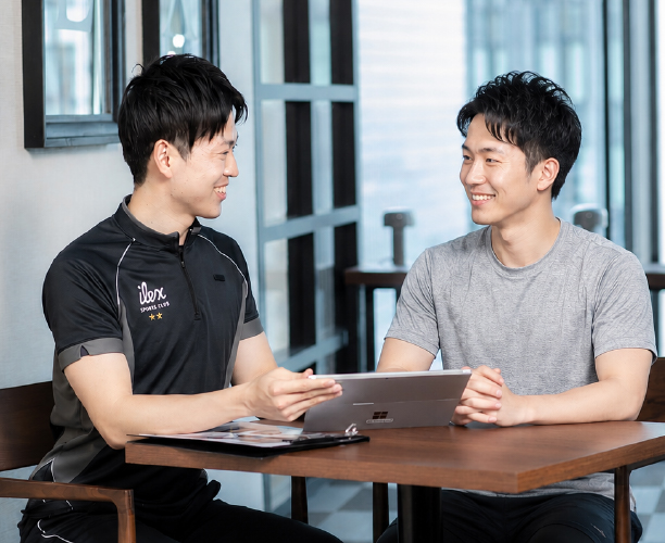 利用男性のスポーツクラブでの目的や悩みを聞く男性スタッフ